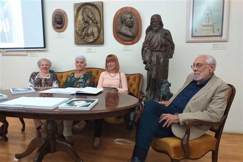 Marija Barbieri na promociji monografije o Marku Vuškoviću u Galeriji <em>Ivan Rendić</em> u knjižnici u Supetru, autorica i umjetnikov unuk upisuju posvete u knjigu 